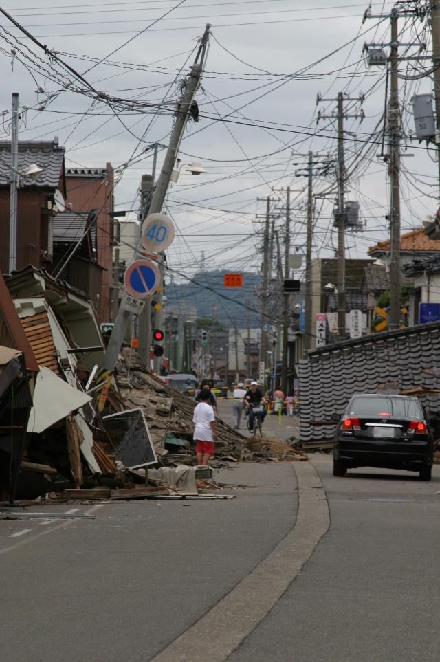 倒壊し、道路をふさいだ家屋の写真