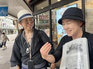 新潟イザベラ・バード研究会と新潟シティガイドの2人。当時の写真を手にガイドをしている。